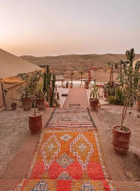 Agafay camp terrace with Moroccan rug and desert sunset